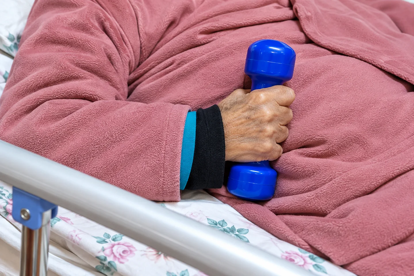 Detalle de una mano sosteniendo una mancuerna azul durante un ejercicio, sin mostrar el rostro.